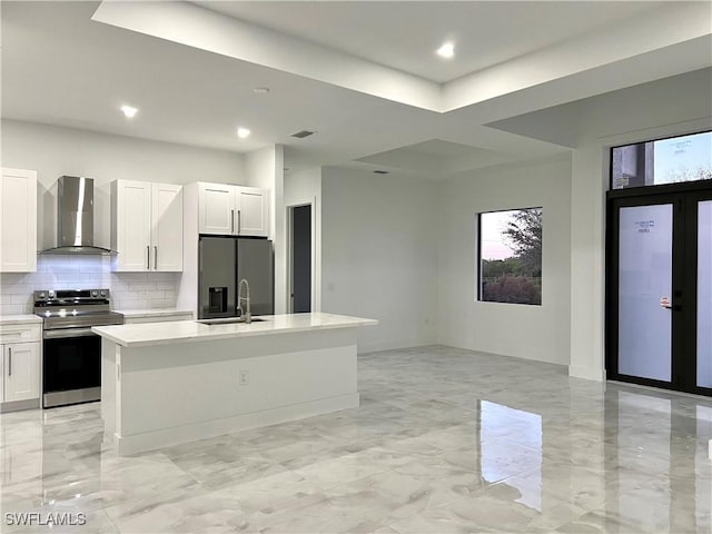 kitchen with white cabinetry, stainless steel appliances, a center island with sink, and wall chimney range hood