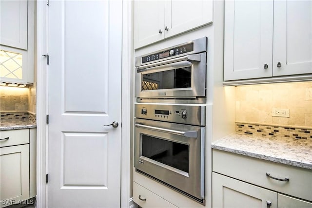 kitchen featuring tasteful backsplash, stainless steel double oven, and light stone countertops