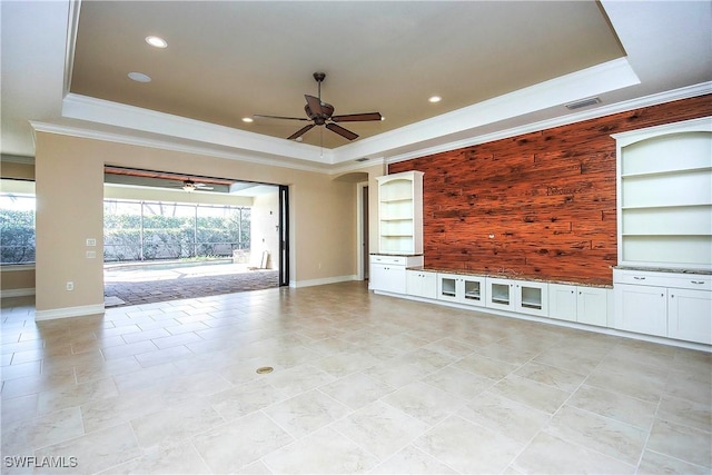 unfurnished living room with a ceiling fan, a tray ceiling, visible vents, and ornamental molding