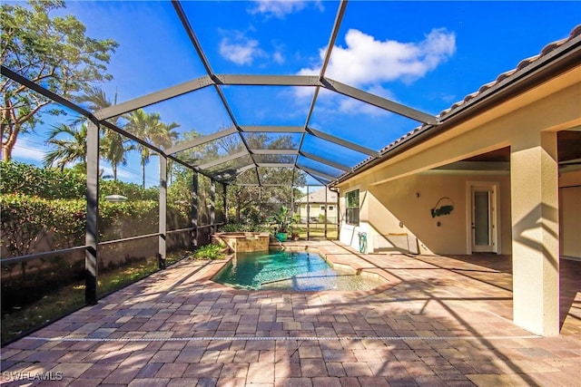 view of pool with a lanai, a pool with connected hot tub, and a patio