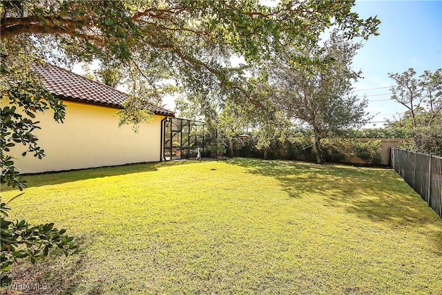 view of yard featuring glass enclosure and a fenced backyard