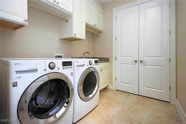 clothes washing area with washing machine and dryer and cabinet space