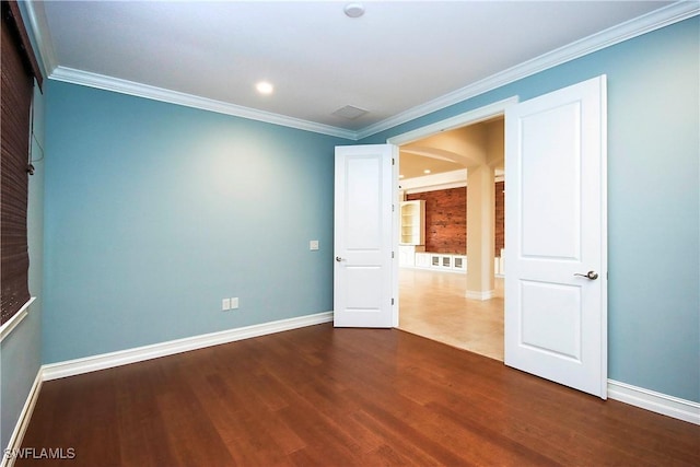 empty room with dark wood-style floors, crown molding, and baseboards