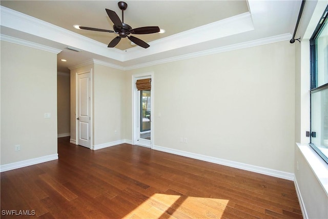 spare room featuring a tray ceiling, visible vents, baseboards, and wood finished floors