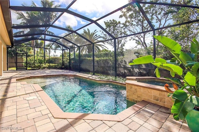 outdoor pool featuring glass enclosure, an in ground hot tub, and a patio