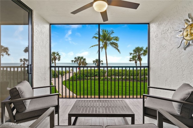 sunroom with a water view and ceiling fan