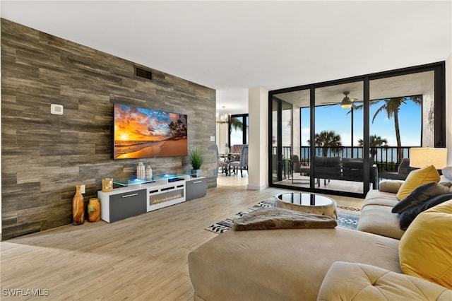 living room featuring ceiling fan, a wall of windows, and light hardwood / wood-style floors