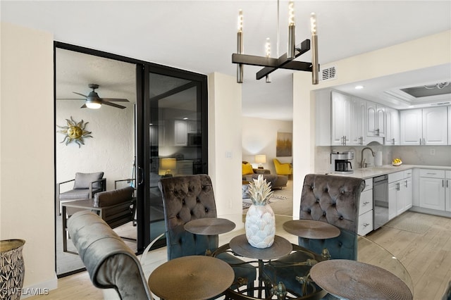 dining area with ceiling fan, sink, and light wood-type flooring