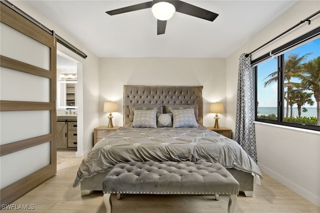 bedroom with ensuite bath, light hardwood / wood-style flooring, and ceiling fan