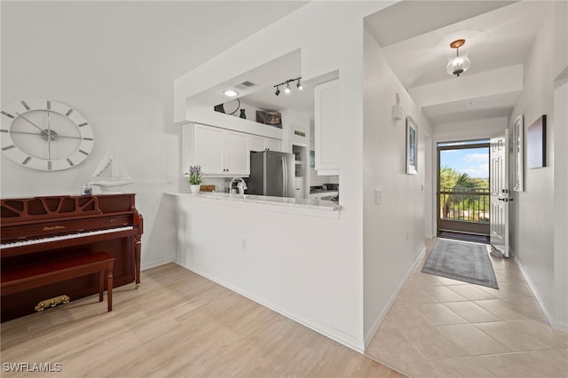 interior space featuring white cabinetry, kitchen peninsula, track lighting, and light wood-type flooring