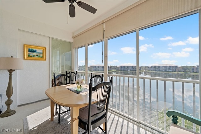 sunroom featuring ceiling fan and a water view