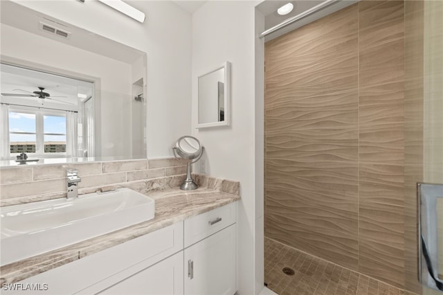 bathroom featuring tiled shower and vanity