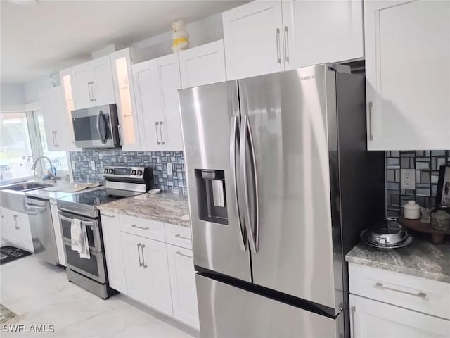 kitchen featuring white cabinetry, appliances with stainless steel finishes, sink, and decorative backsplash