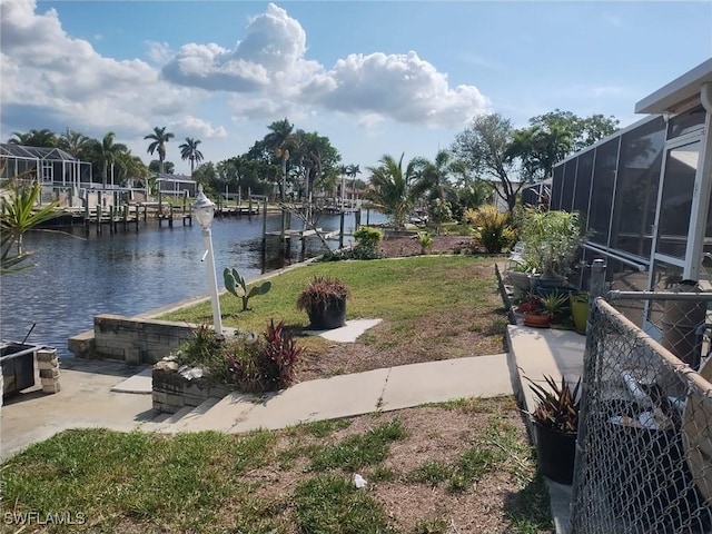 view of yard with a water view, a lanai, and a dock