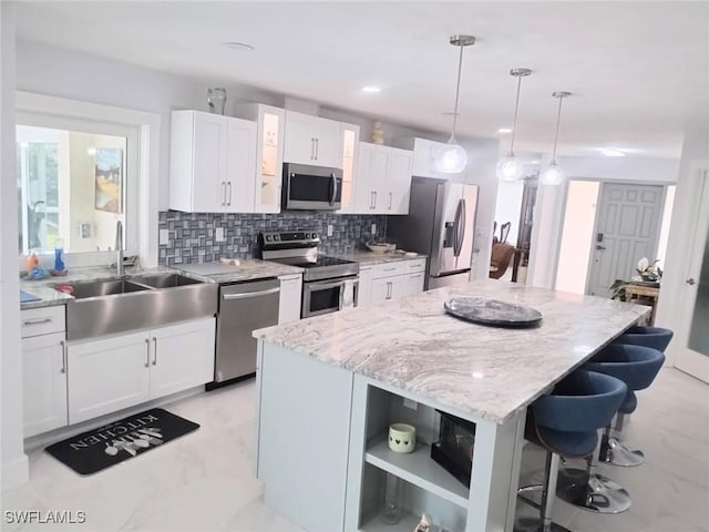 kitchen featuring white cabinetry, stainless steel appliances, a center island, and sink