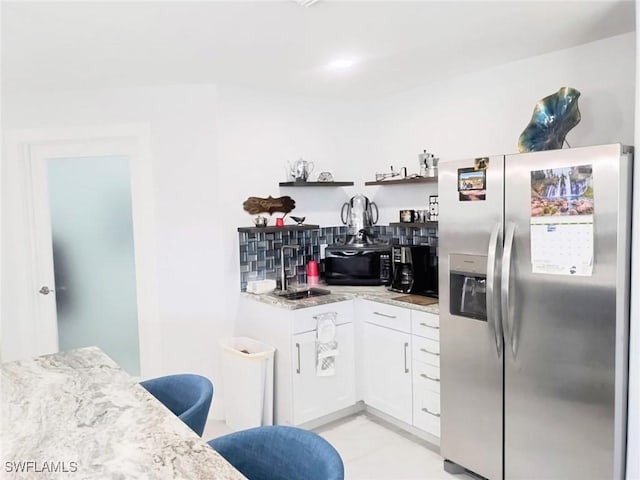 kitchen with sink, white cabinets, decorative backsplash, stainless steel fridge with ice dispenser, and light stone countertops