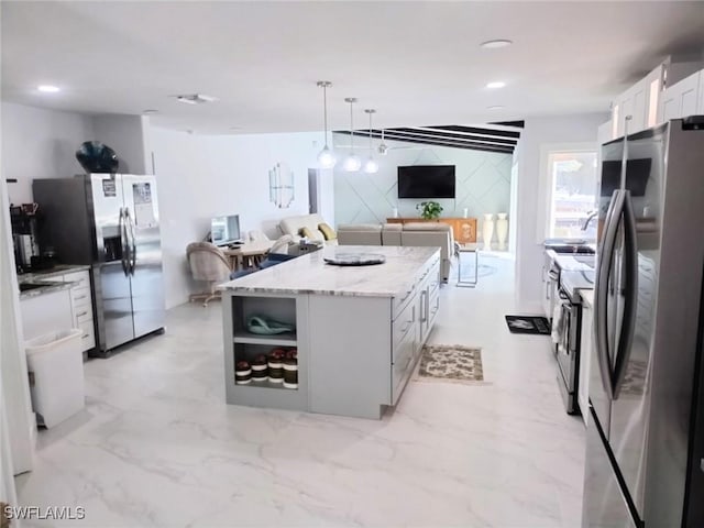 kitchen featuring stainless steel appliances, light stone countertops, white cabinets, a kitchen island, and decorative light fixtures