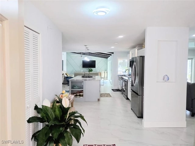 kitchen featuring sink, white cabinetry, a center island, hanging light fixtures, and appliances with stainless steel finishes