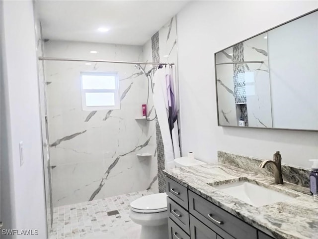 bathroom featuring vanity, a tile shower, and toilet