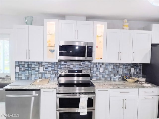 kitchen featuring tasteful backsplash, stainless steel appliances, light stone countertops, and white cabinets