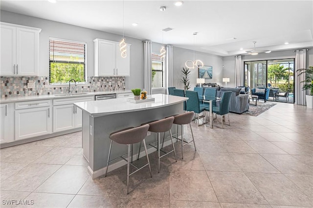 kitchen featuring white cabinetry, hanging light fixtures, sink, and a center island