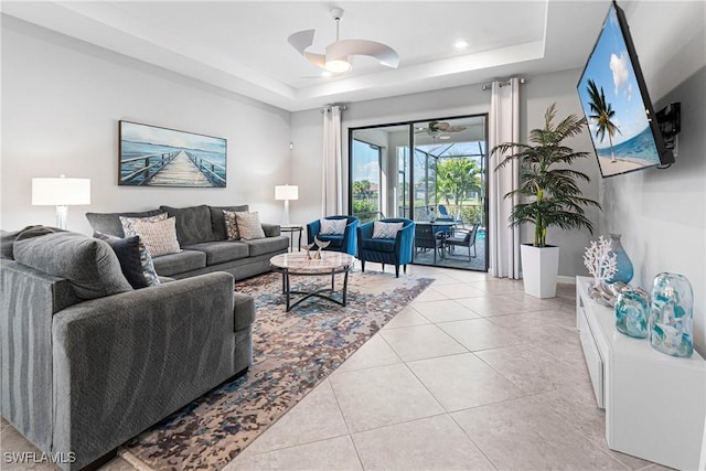 living room featuring a tray ceiling, baseboards, recessed lighting, ceiling fan, and light tile patterned floors