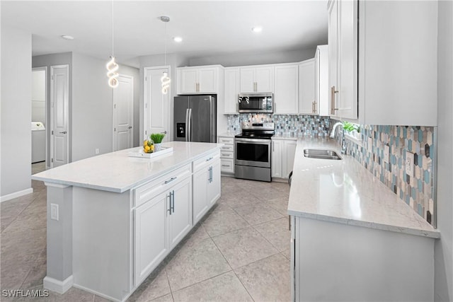 kitchen with sink, stainless steel appliances, white cabinets, a kitchen island, and decorative light fixtures