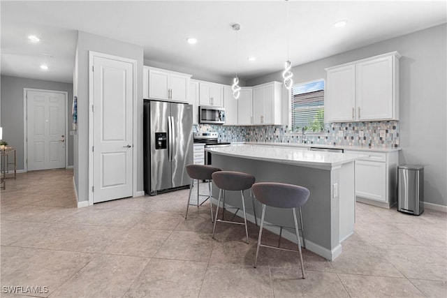 kitchen with decorative light fixtures, stainless steel appliances, a center island, and white cabinets