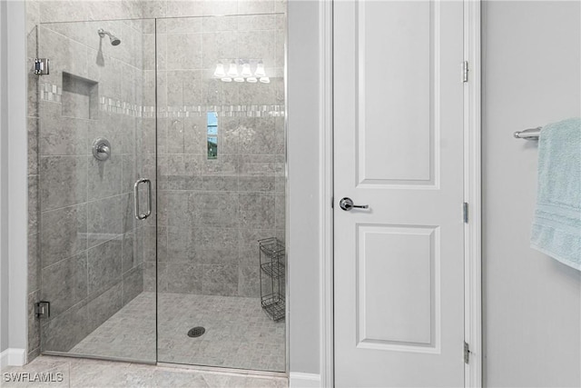 full bathroom with a shower stall and baseboards
