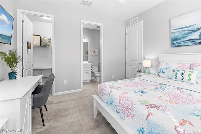 bedroom with light colored carpet, baseboards, a walk in closet, and visible vents