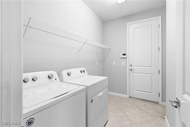 laundry room featuring washing machine and clothes dryer, baseboards, laundry area, and light tile patterned floors