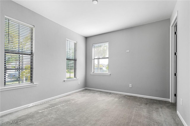 carpeted empty room featuring baseboards
