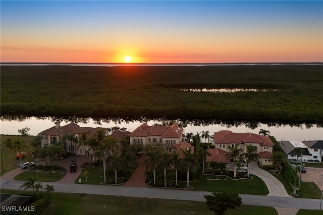 aerial view at dusk with a water view and a residential view