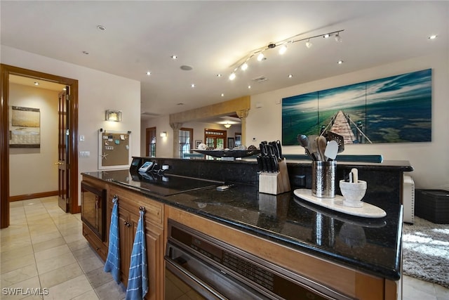 bar featuring black electric stovetop, light tile patterned flooring, oven, and baseboards