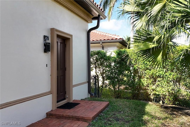 property entrance featuring a tiled roof and stucco siding