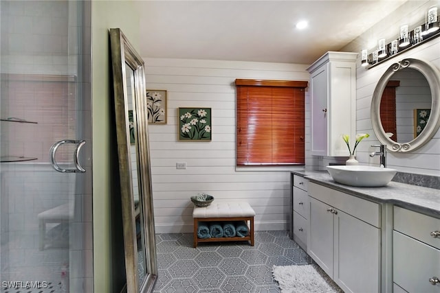 full bath featuring a shower with door, wooden walls, and vanity