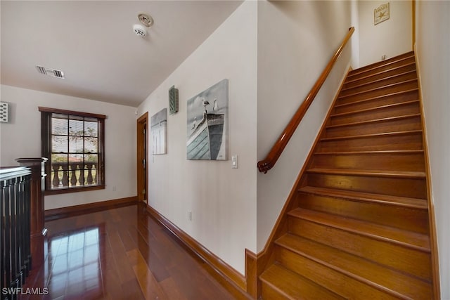 stairway featuring wood finished floors, visible vents, and baseboards