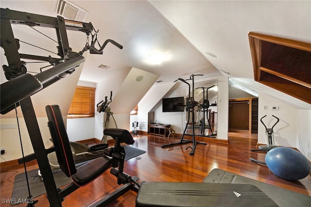 exercise room with lofted ceiling, baseboards, visible vents, and wood finished floors