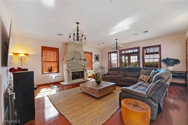 living room with a fireplace, visible vents, a notable chandelier, and wood finished floors