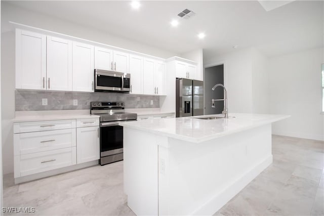 kitchen with white cabinetry, stainless steel appliances, sink, and an island with sink