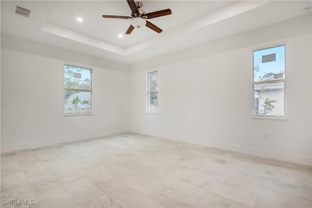 spare room with a tray ceiling and ceiling fan