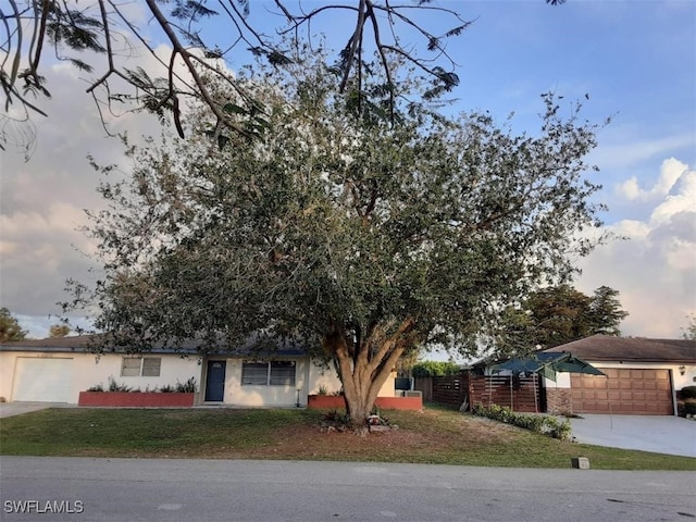 view of property hidden behind natural elements featuring a garage and a yard