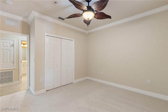 unfurnished bedroom featuring ornamental molding, light carpet, and a closet