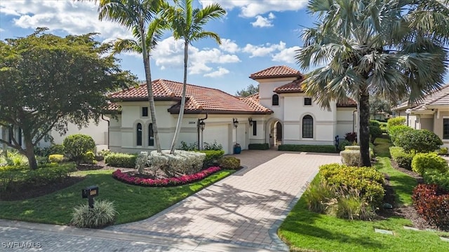 mediterranean / spanish-style home with a garage and a front lawn