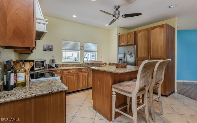 kitchen featuring sink, light tile patterned floors, a breakfast bar, stainless steel appliances, and a center island