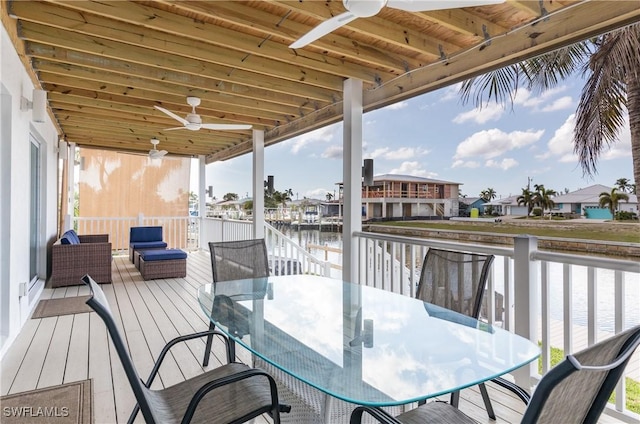 wooden deck with a water view, ceiling fan, and outdoor lounge area