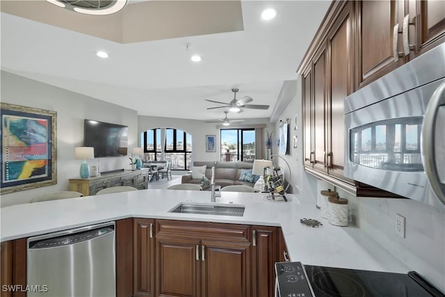 kitchen with stainless steel appliances, sink, ceiling fan, and kitchen peninsula