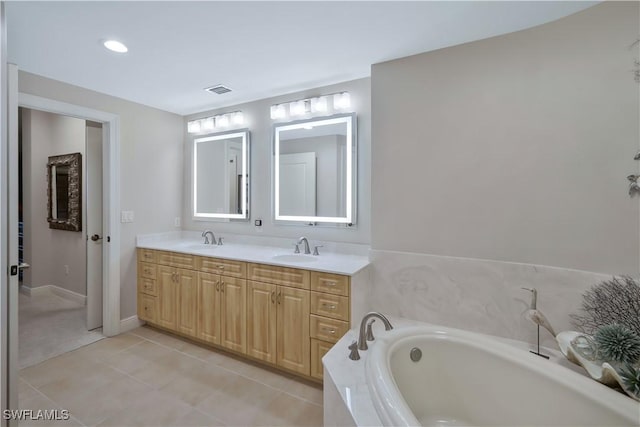 bathroom with tile patterned flooring, vanity, and a relaxing tiled tub