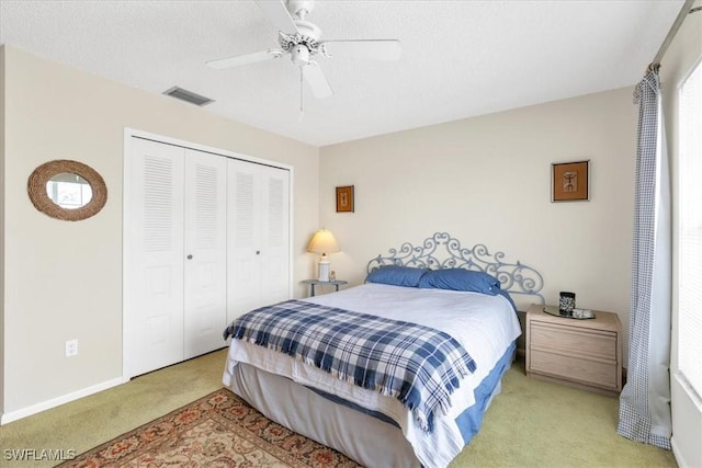 carpeted bedroom with ceiling fan, a closet, and a textured ceiling