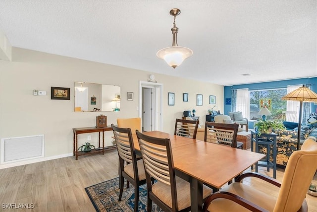 dining area featuring a textured ceiling and light wood-type flooring